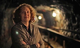 Julia Wolfe stands with her arms crossed in an underground mineshaft.