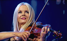 A close up photo of a young blond woman playing the fiddle.