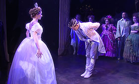 The prince bows to Cinderella before they begin to dance as a crowd watches on.