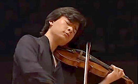 Jackiw closes his eyes and passionately plays the violin on a dark stage.