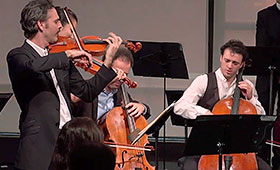 Two violinists and two cellists perform on stage.