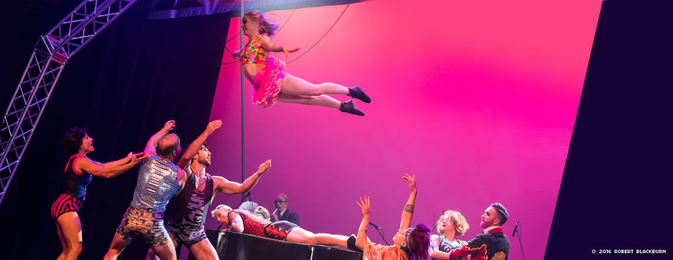 A member of Circus Oz flies into the arms of three acrobats while other members of Circus Oz watch.