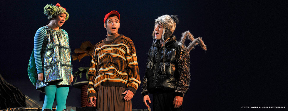 Actors dressed in costumes depicting a fly, a worm, and a spider sing in unison.