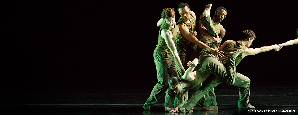 A tangled group of four dancers features one positioned face down with her right hand on the ground and held in place by another while two others extend their arms down to her back and another reaches out from the group to an unseen dancer with his right arm.