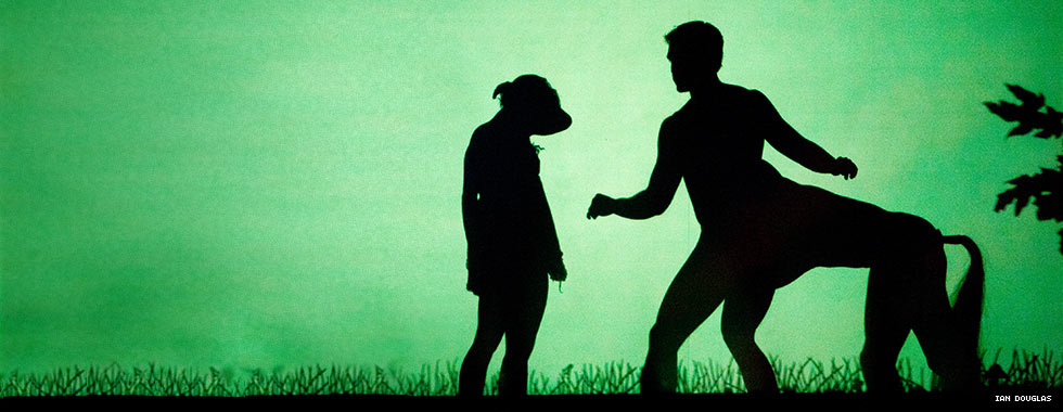 A silhouette of a dancer depicts a young girl wearing an animal head as she stands next to the silhouette of dancers posed in the shape of a centaur in Pilobolus' "Shadowland."