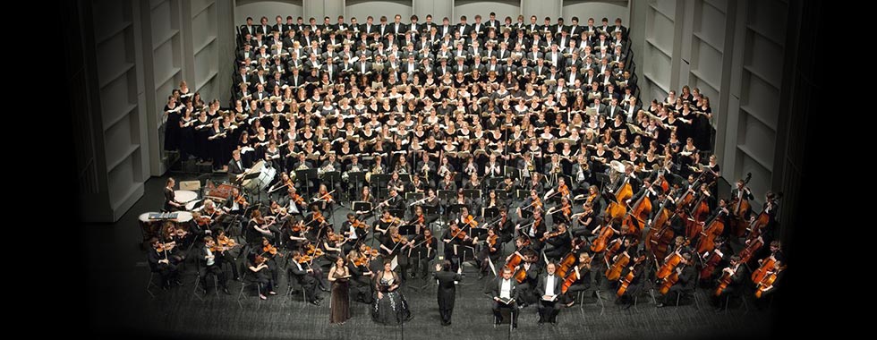 An orchestra and choir perform on stage.