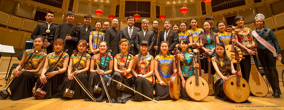 Sounds of China—the men wearing dark suits and the women dressed in ornate tunics—hold their traditional Chinese instruments as they smile for the camera.
