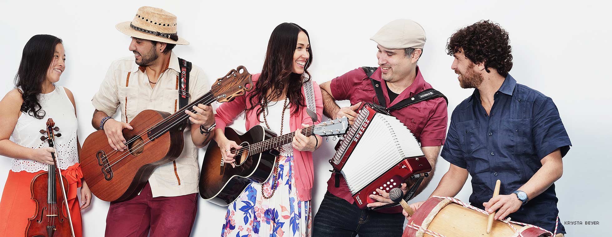 Five Latinx musician hold their traditional Mexican instruments and smile. 