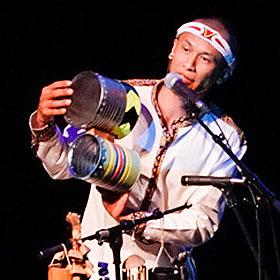 A musician holds up a percussion instrument made from large upcycled aluminum food cans.