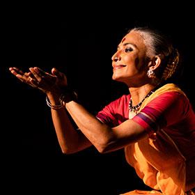 Odissi dancer Bijayini Satpathy raises her hands together in front of her face.