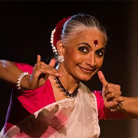 Indian dancer Bijayini Satpathy raises her hands in front of her face in a traditional Odissi form.