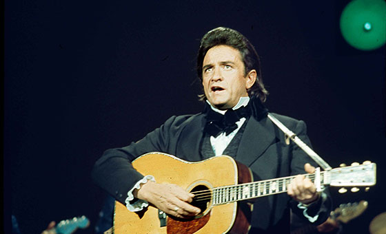 Johnny Cash sings on stage while playing the guitar.
