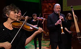 Members of an orchestra—including string musicians, an oboeist and a double-bassist—perform.