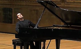 Inon Barnatan closes his eyes and looks upward while playing the piano.