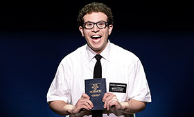 A man in a white shirt and black tie holds a bible in the air.