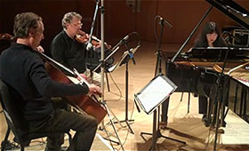 Cellist David Finckel, violinist Philip Setzer, and pianist Wu Han sit close together while they record in a music studio.