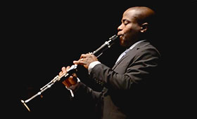 A photograph captures the profile of Anthony McGill while he plays his clarinet.