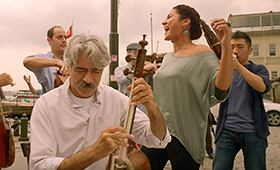 Four musicians perform on a street.
