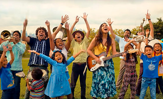 Sonia sings in a field surrounded by singing children and musicians from her band.