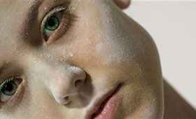 A close-up photo of a young woman's face lightly covered with white powder.
