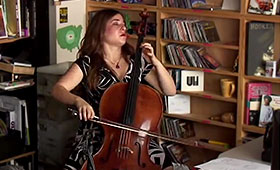 Alisa Weilerstein sits at a music stand in front of various bookcases in a photo taken during an NPR Tiny Desk Concert.