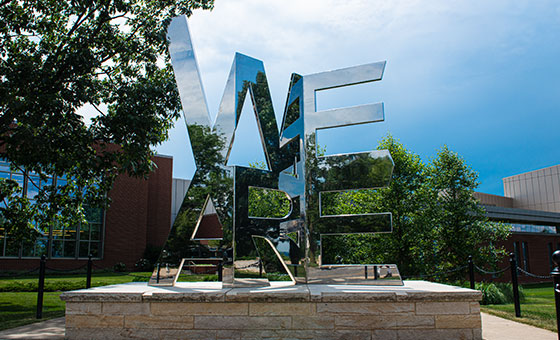 A large metal sculpture in the shape of the stacked words We Are.