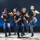 Five step dancers perform in a row on stage.