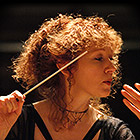 Sorrell holds up her baton while conducting the orchestra.