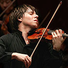 A violinist closes his eyes and throws his head back while he plays a violin.