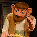 A bearded, big-eared, larger-than-life puppet depicts the play’s title character.