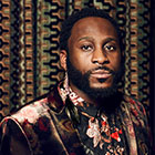 Michael Mwenso sits for a portrait wearing a floral pattern suit.