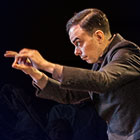 A man gestures with his hands as he conducts an orchestra.