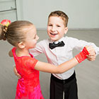 A young boy and girl dance in a ballroom.