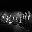 The ten vocalists of a cappella group Straight No Chaser hold drinks and smile for the camera.