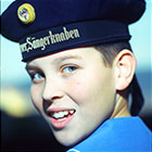 A choirboy, wearing an official choir sailor’s hat, smiles at the camera.