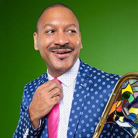 A man smiles as he straightens his tie.