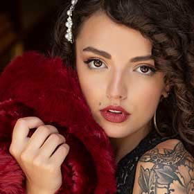 Emmaline holds a fur shawl close to her face.