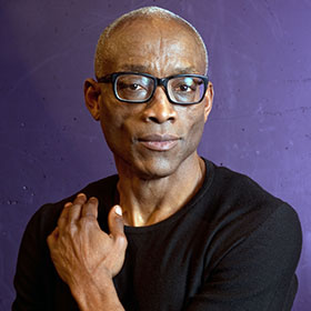 Bill T. Jones looks at the camera with his left hand resting on his shoulder.