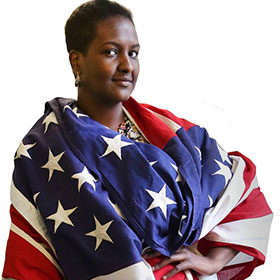 Sharifa Ali stands draped in the flag of the United States.